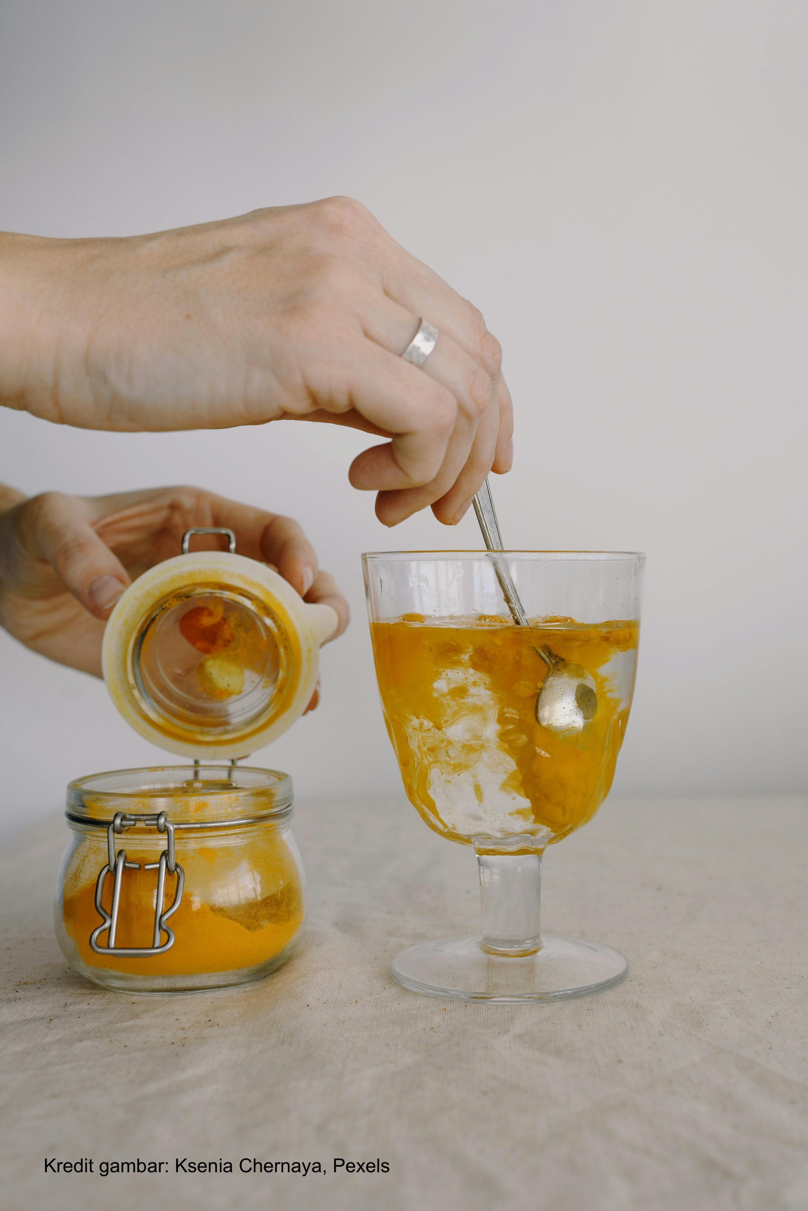 Crop hands adding turmeric in glass of hot water in morning